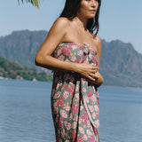 woman with brown hair wearing a teal pareo wrap with shell and pua print 