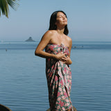 woman with brown hair wearing a teal pareo wrap with shell and pua print 