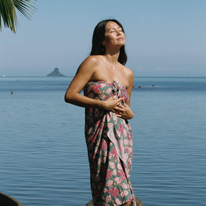 woman with brown hair wearing a teal pareo wrap with shell and pua print 