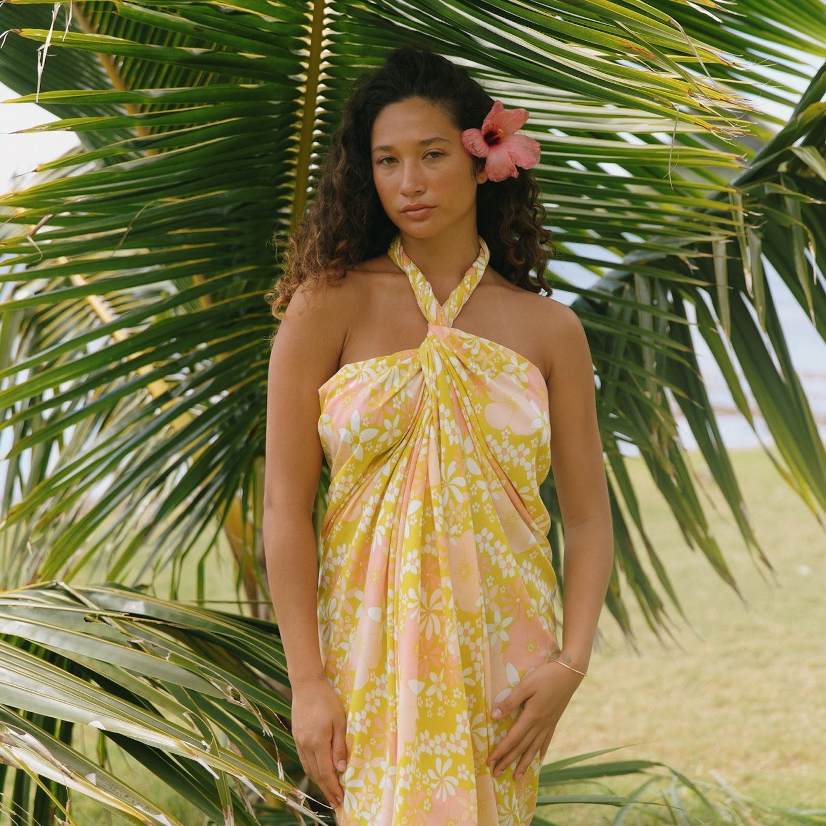 woman with brown hair wearing green yellow colored pareo with white and pink flower print