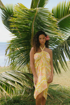 woman with brown hair wearing green yellow colored pareo with white and pink flower print