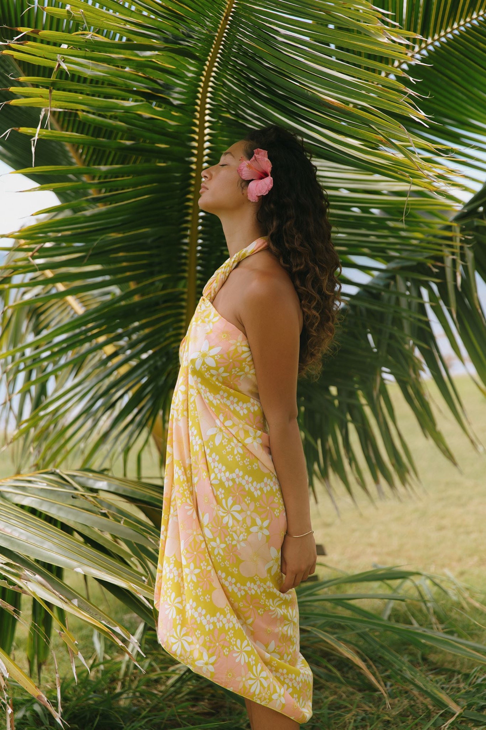 woman with brown hair wearing green yellow colored pareo with white and pink flower print