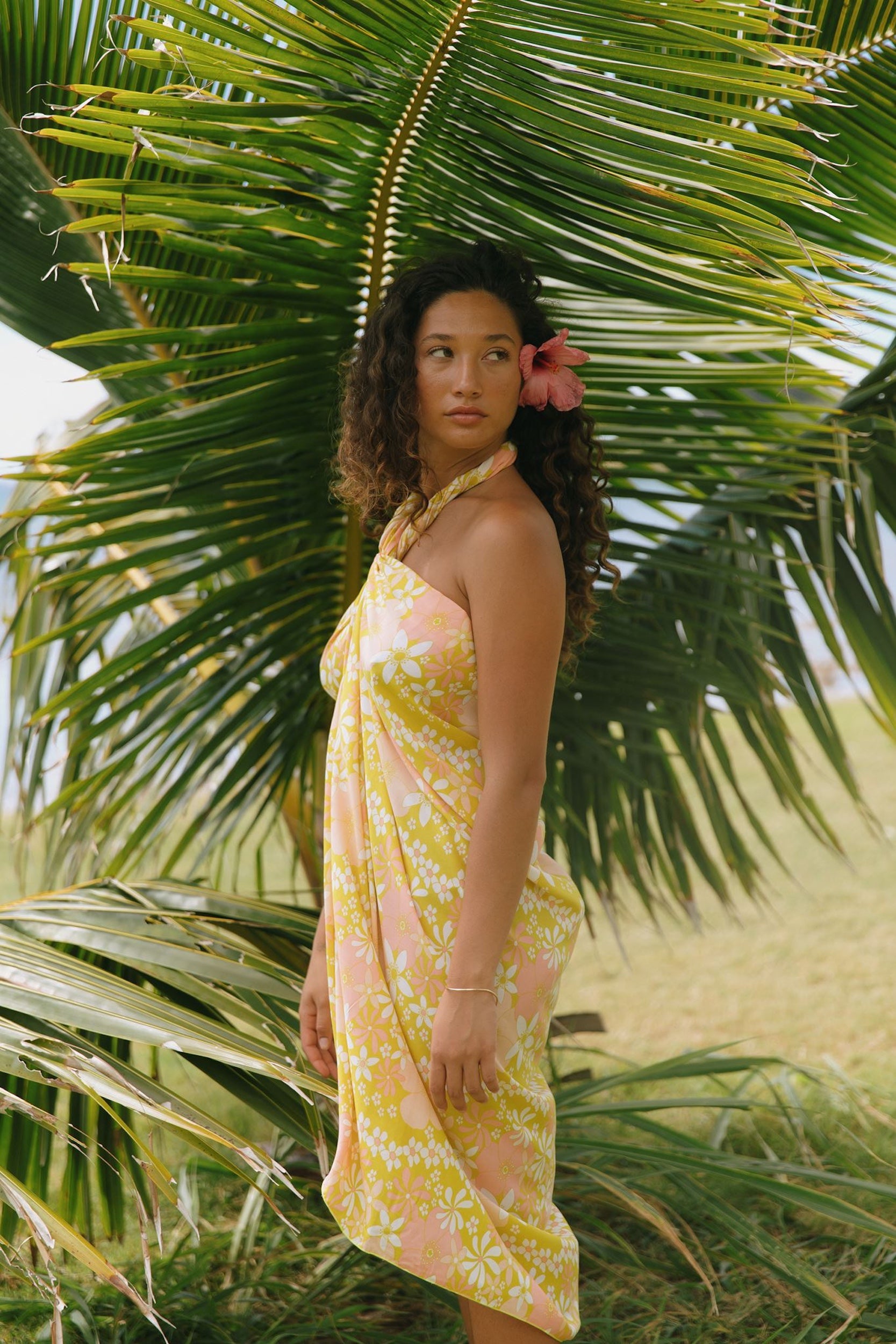 woman with brown hair wearing green yellow colored pareo with white and pink flower print