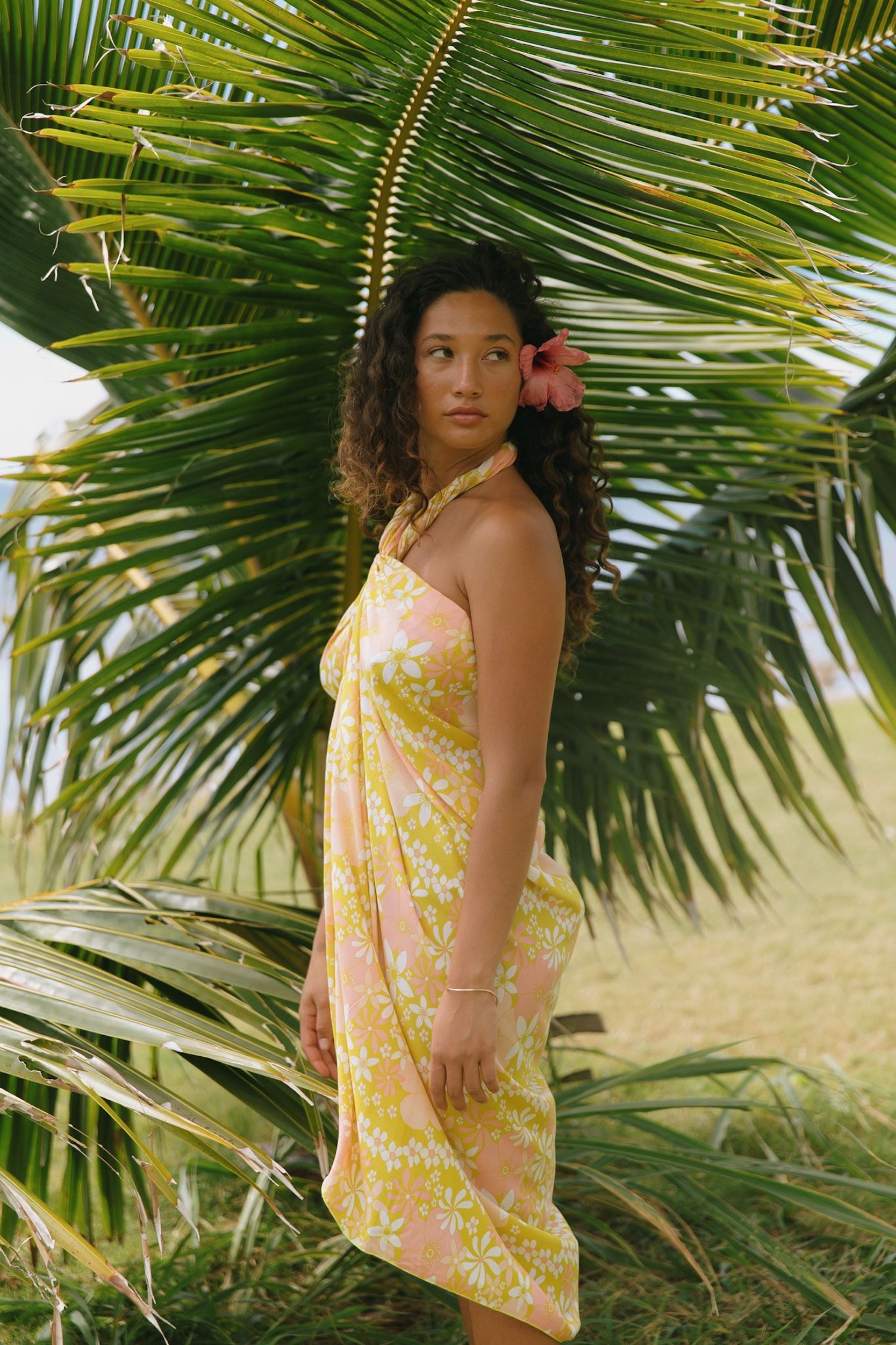 woman with brown hair wearing green yellow colored pareo with white and pink flower print