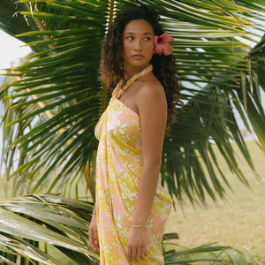 woman with brown hair wearing green yellow colored pareo with white and pink flower print