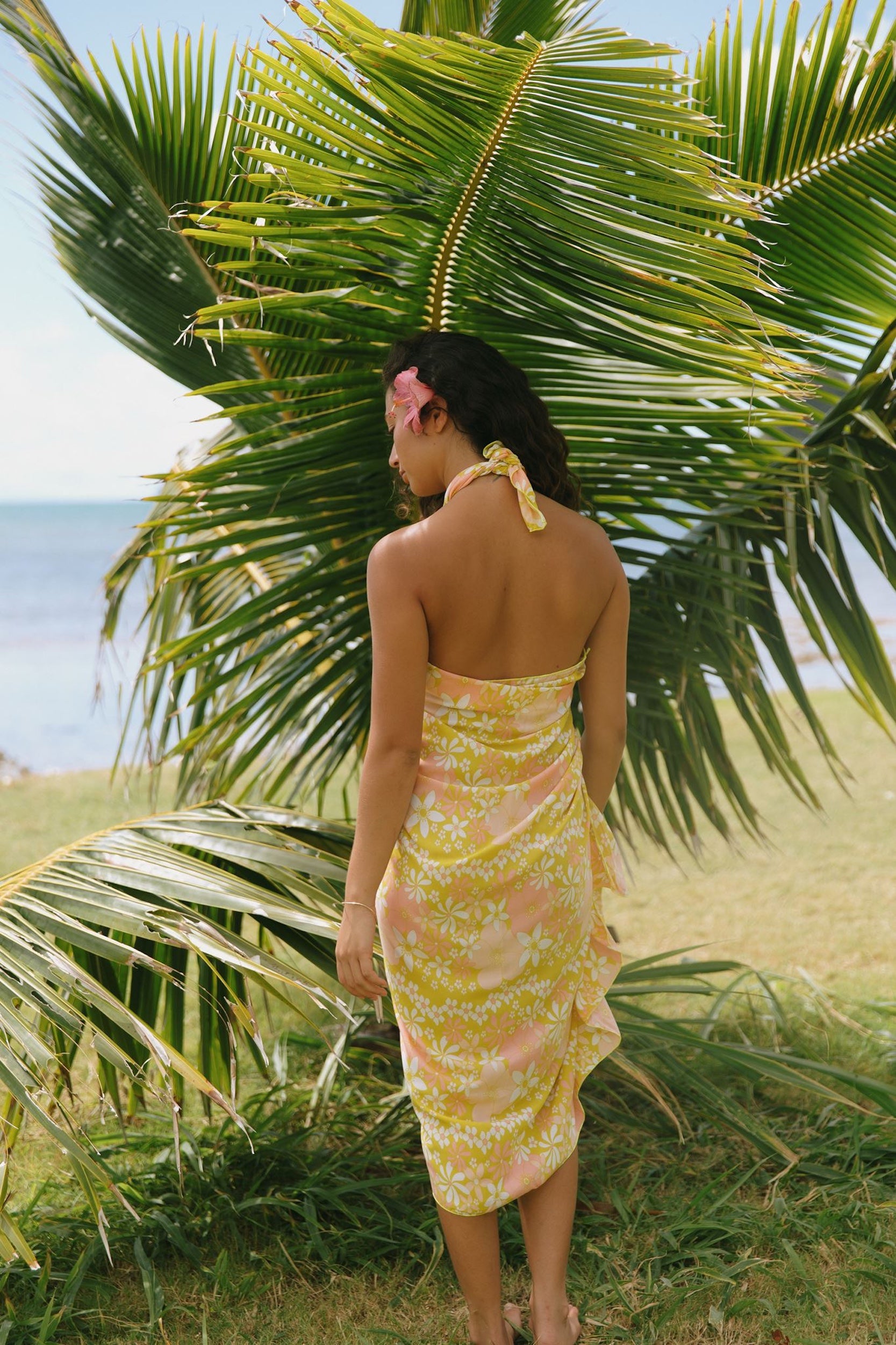 woman with brown hair wearing green yellow colored pareo with white and pink flower print