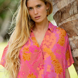 woman wearing a pink v neck button up mini dress with lei print