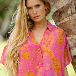 woman wearing a pink v neck button up mini dress with lei print