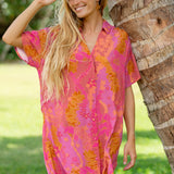 woman wearing a pink v neck button up mini dress with lei print