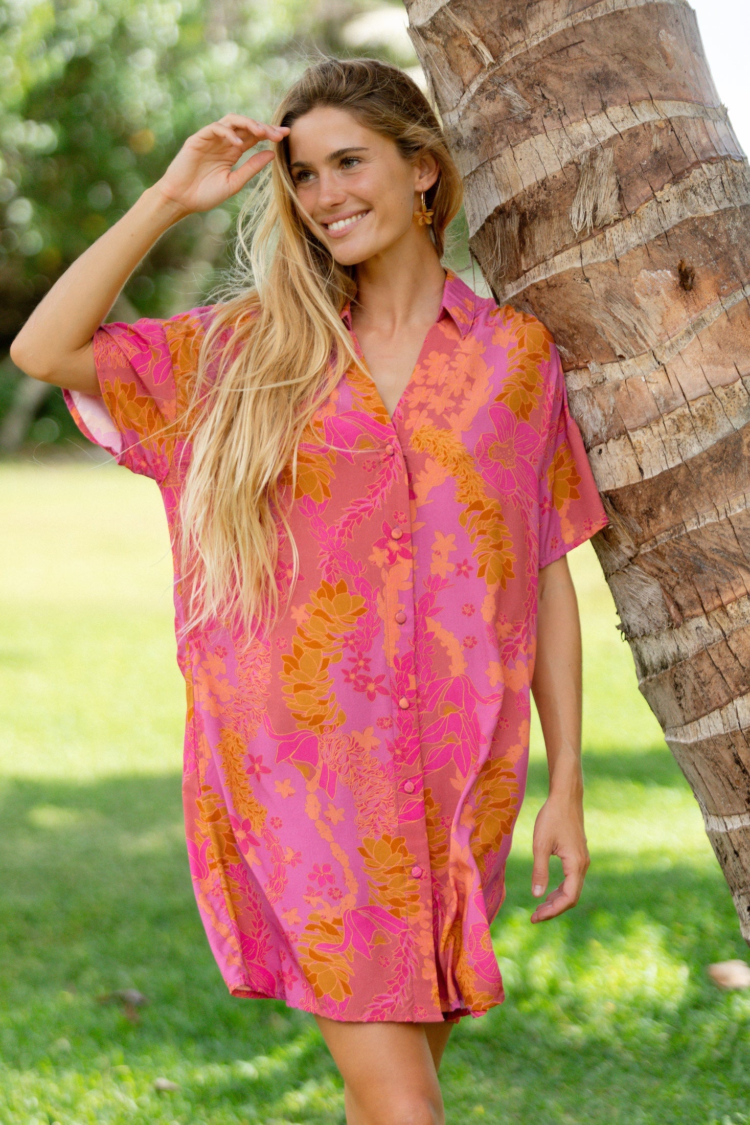 woman wearing a pink v neck button up mini dress with lei print