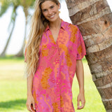 woman wearing a pink v neck button up mini dress with lei print