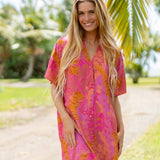 woman wearing a pink v neck button up mini dress with lei print
