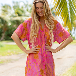woman wearing a pink v neck button up mini dress with lei print