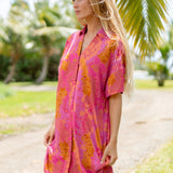 woman wearing a pink v neck button up mini dress with lei print