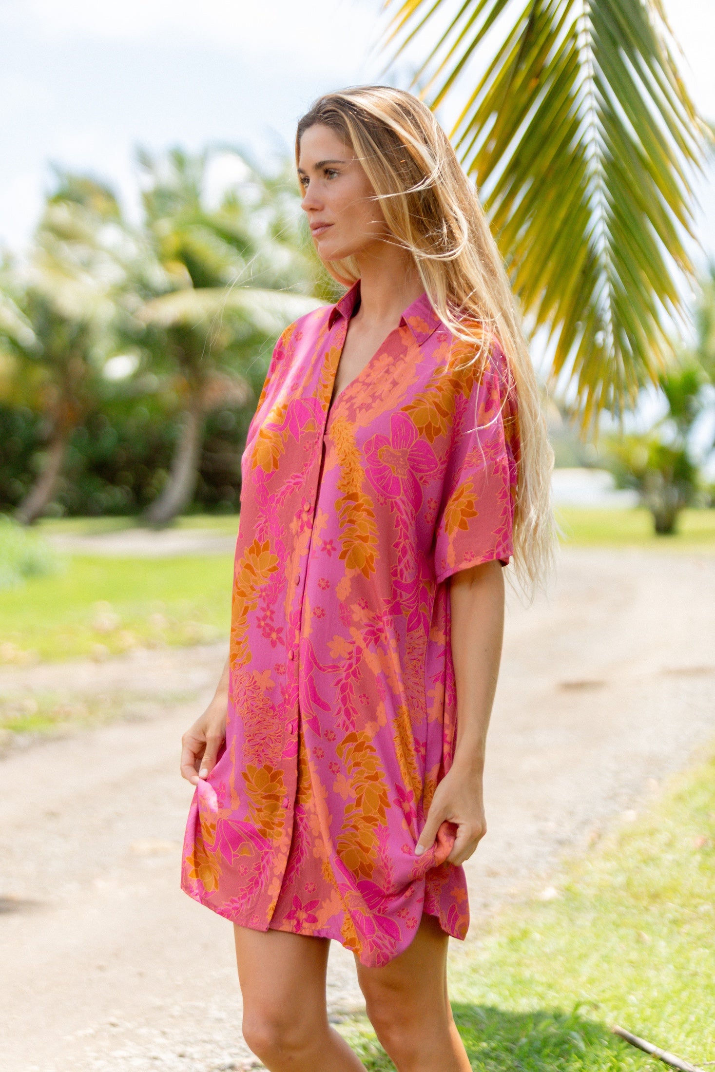 woman wearing a pink v neck button up mini dress with lei print