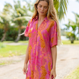 woman wearing a pink v neck button up mini dress with lei print