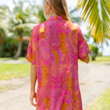 woman wearing a pink v neck button up mini dress with lei print