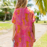 woman wearing a pink v neck button up mini dress with lei print