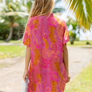 woman wearing a pink v neck button up mini dress with lei print