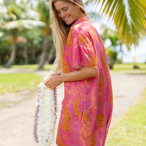 woman wearing a pink v neck button up mini dress with lei print