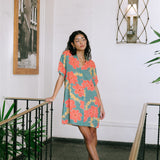 woman with brown hair wearing collared button down dress with orange and yellow lei pua print