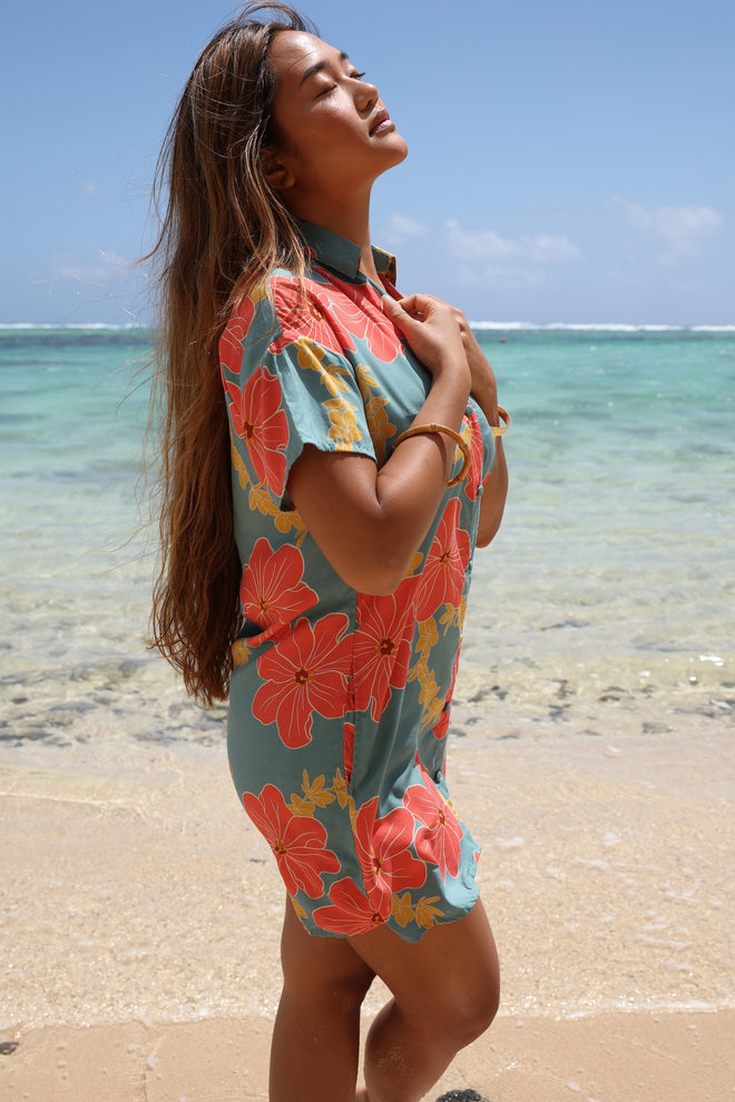 woman with brown hair wearing collared button down dress with orange and yellow lei pua print