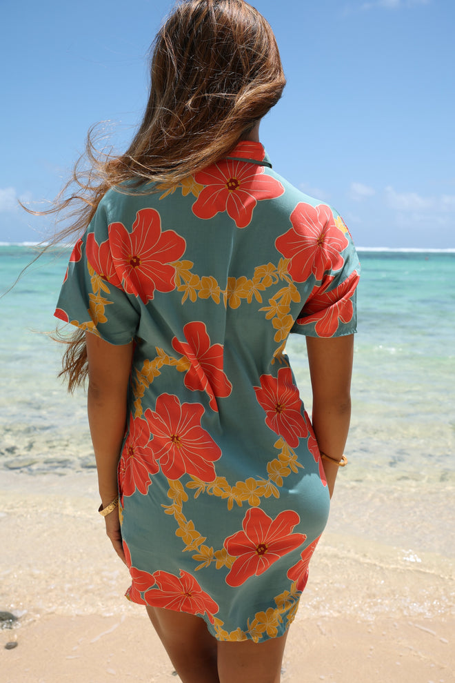 woman with brown hair wearing collared button down dress with orange and yellow lei pua print