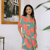 woman with brown hair wearing collared button down dress with orange and yellow lei pua print