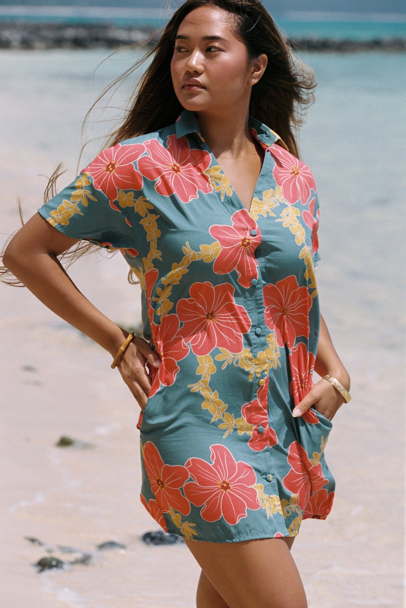 woman with brown hair wearing collared button down dress with orange and yellow lei pua print