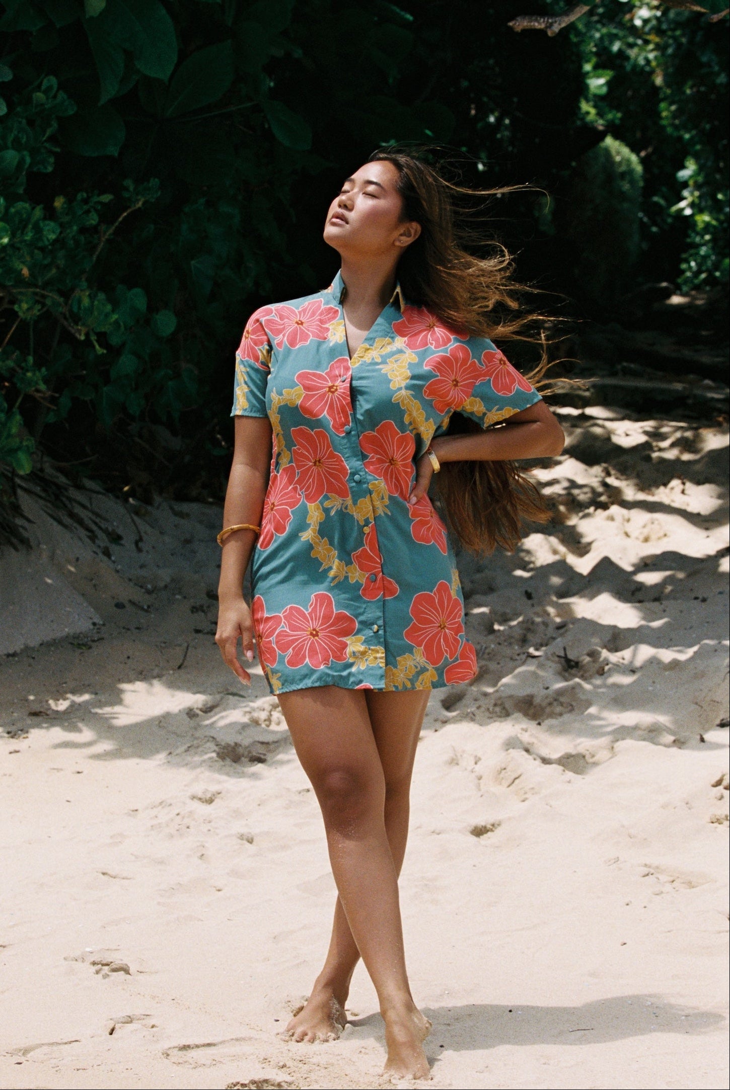 woman with brown hair wearing collared button down dress with orange and yellow lei pua print