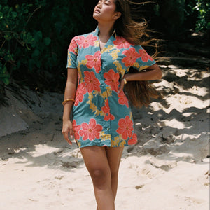 woman with brown hair wearing collared button down dress with orange and yellow lei pua print