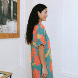 woman with brown hair wearing collared button down dress with orange and yellow lei pua print