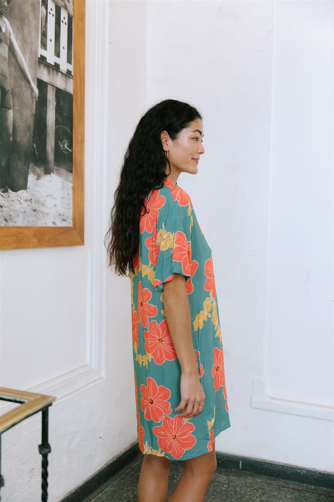 woman with brown hair wearing collared button down dress with orange and yellow lei pua print
