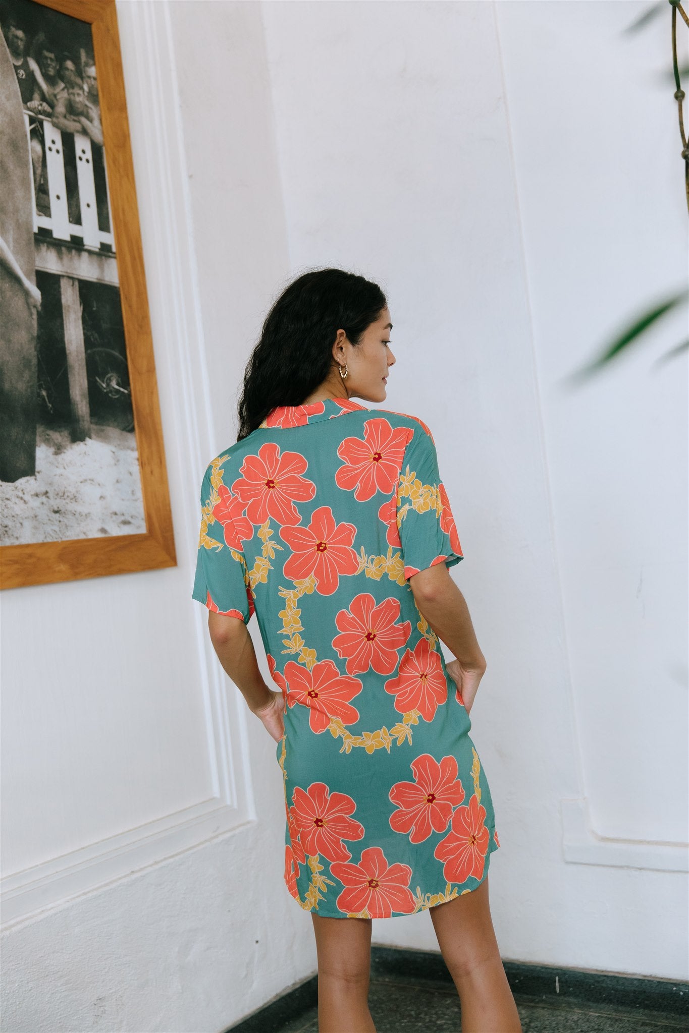 woman with brown hair wearing collared button down dress with orange and yellow lei pua print