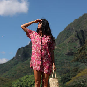 woman with brown hair wearing a collared button up dress with shells and pua print in pink color