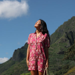 woman with brown hair wearing a collared button up dress with shells and pua print in pink color