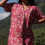 woman with brown hair wearing a collared button up dress with shells and pua print in pink color
