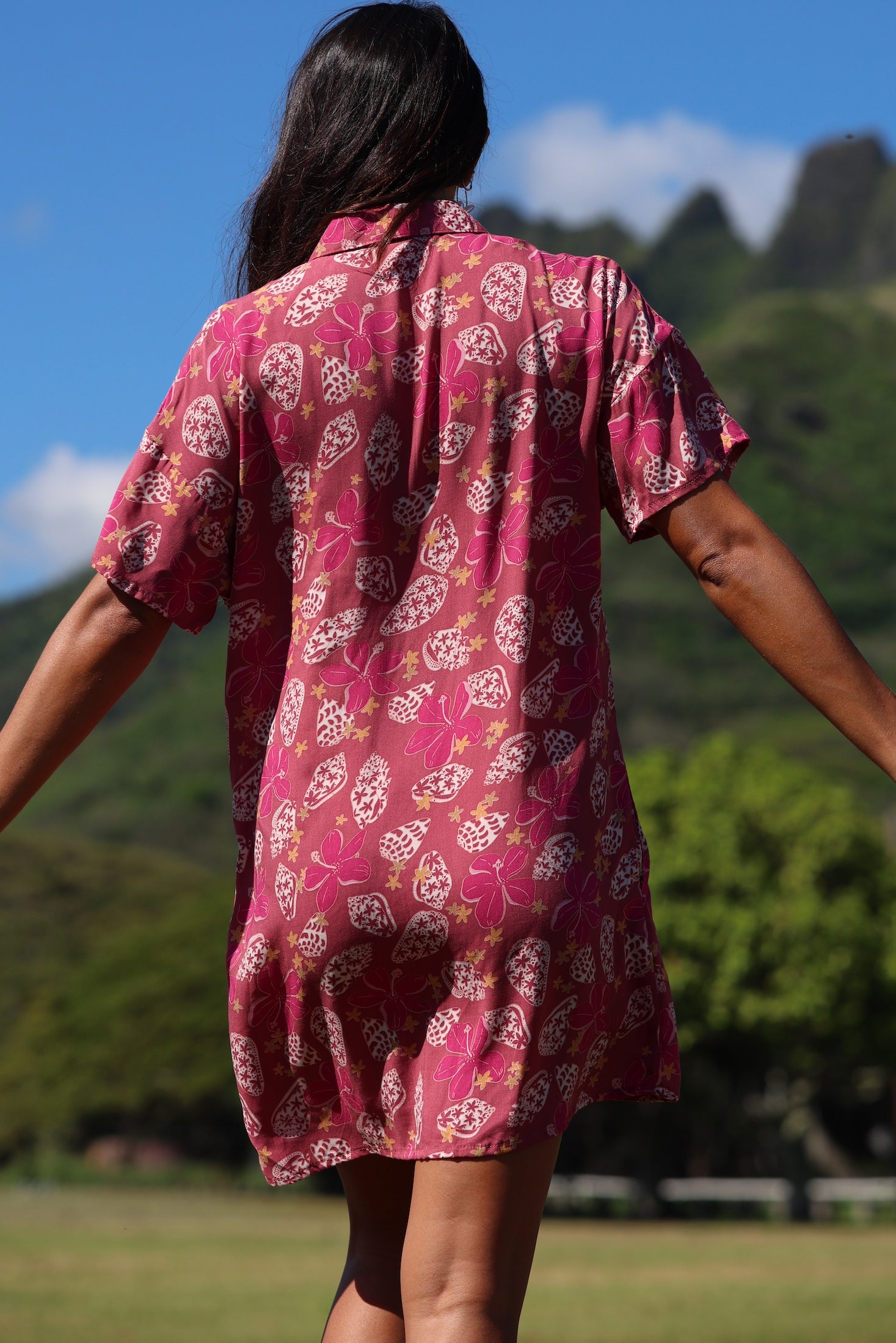 woman with brown hair wearing a collared button up dress with shells and pua print in pink color