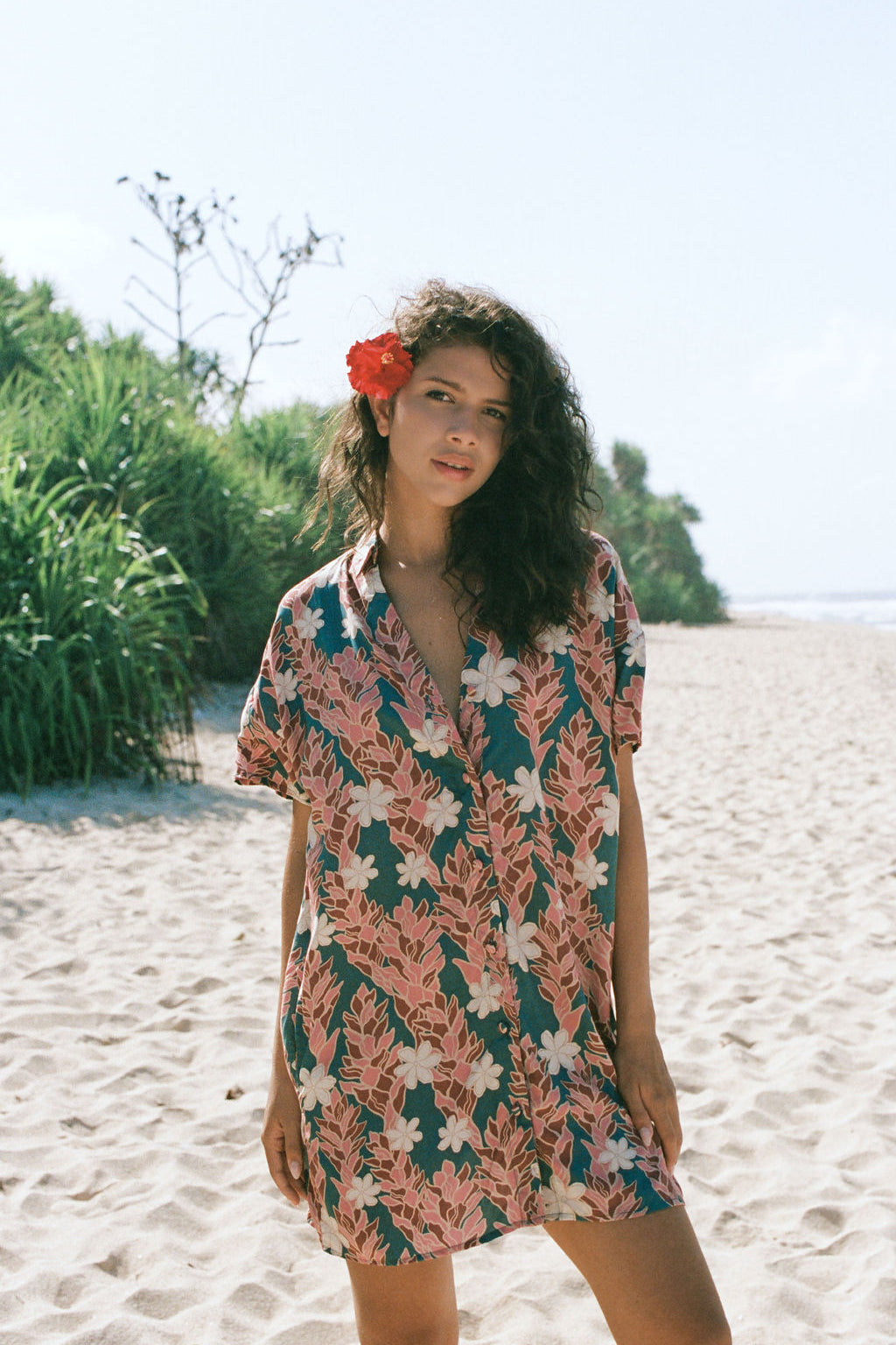 woman with brown hair wearing button up dress with red ginger and tiare print