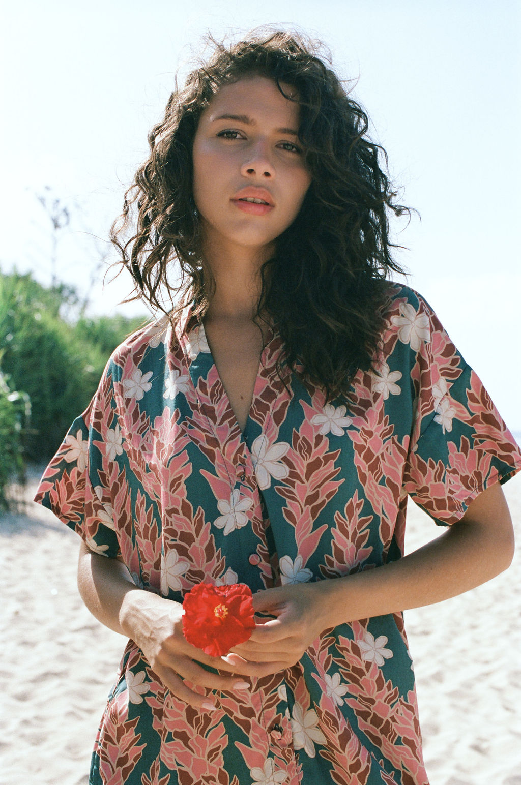 woman with brown hair wearing button up dress with red ginger and tiare print