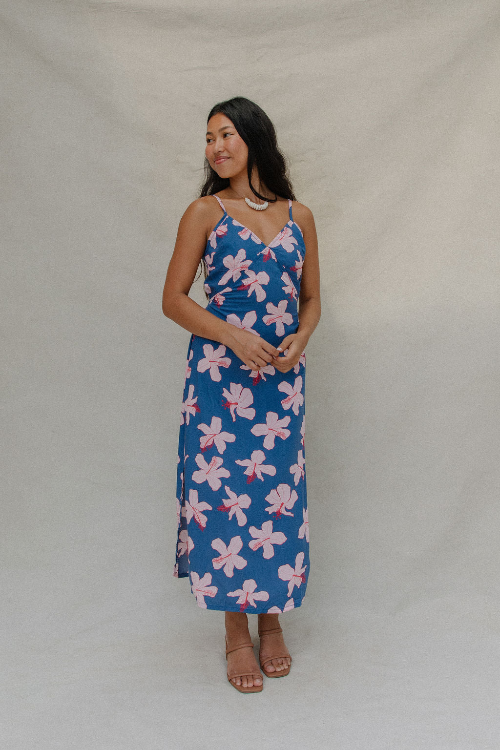 woman with brown hair wearing a navy v neck tie back dress with white hibiscus print