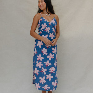 woman with brown hair wearing a navy v neck tie back dress with white hibiscus print