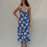 woman with brown hair wearing a navy v neck tie back dress with white hibiscus print