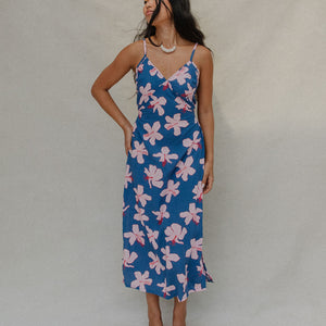 woman with brown hair wearing a navy v neck tie back dress with white hibiscus print