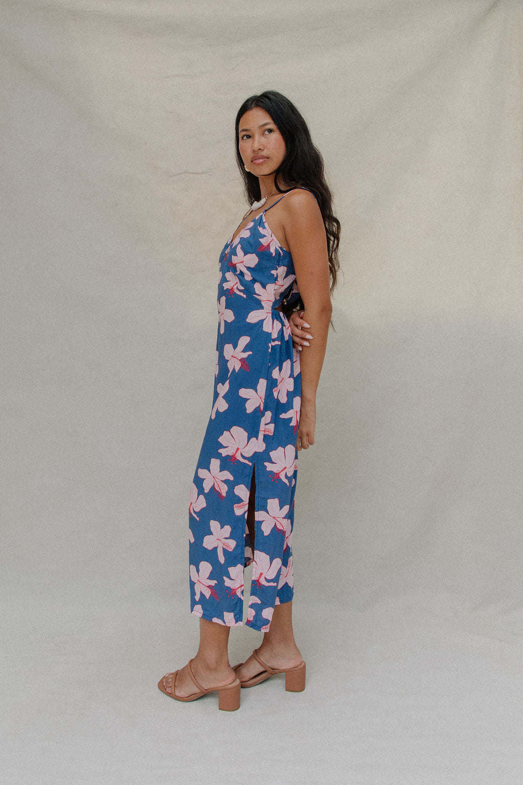 woman with brown hair wearing a navy v neck tie back dress with white hibiscus print