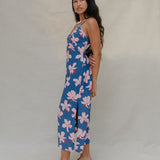 woman with brown hair wearing a navy v neck tie back dress with white hibiscus print