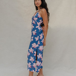 woman with brown hair wearing a navy v neck tie back dress with white hibiscus print