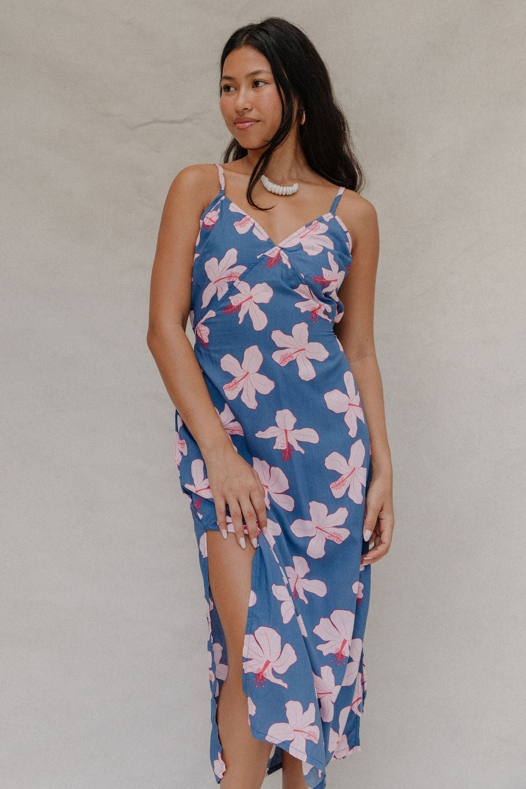 woman with brown hair wearing a navy v neck tie back dress with white hibiscus print