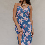 woman with brown hair wearing a navy v neck tie back dress with white hibiscus print