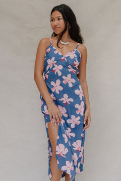 woman with brown hair wearing a navy v neck tie back dress with white hibiscus print